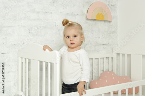Adorable cheerful baby girl in the crib in the nursery room