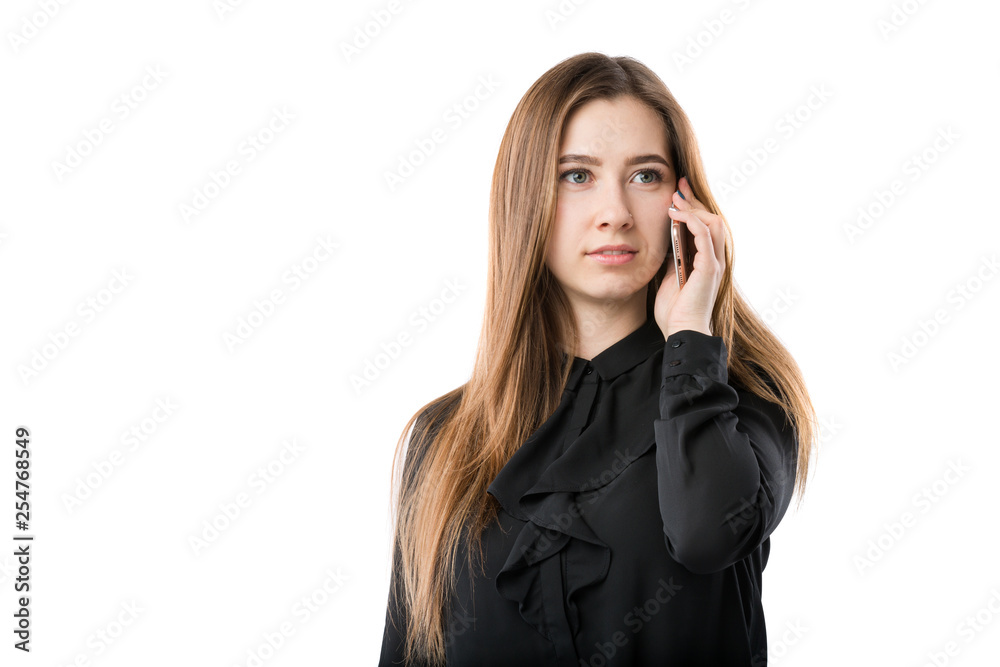 Portrait of a young caucasian woman in a black shirt and long flowing hair using hand-holding technology phone, taking a call against white isolate background Portrait of a young caucasian woman in a black shirt and long flowing hair using hand-holding technology phone, taking a call against white isolate background