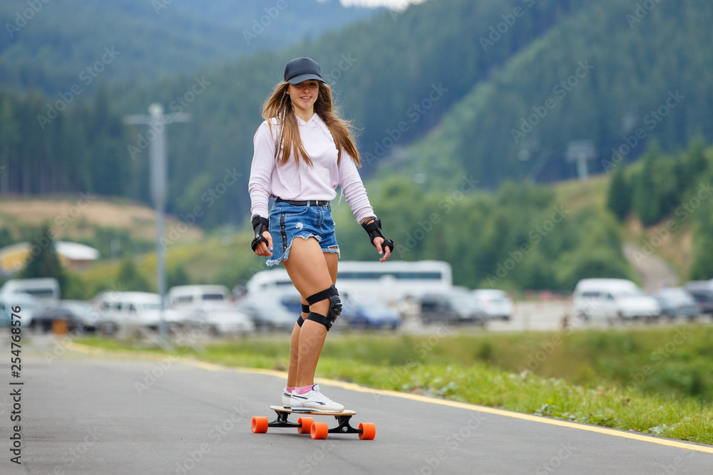 Young girl longboarding downhill on hillside road Stock Photo | Adobe Stock
