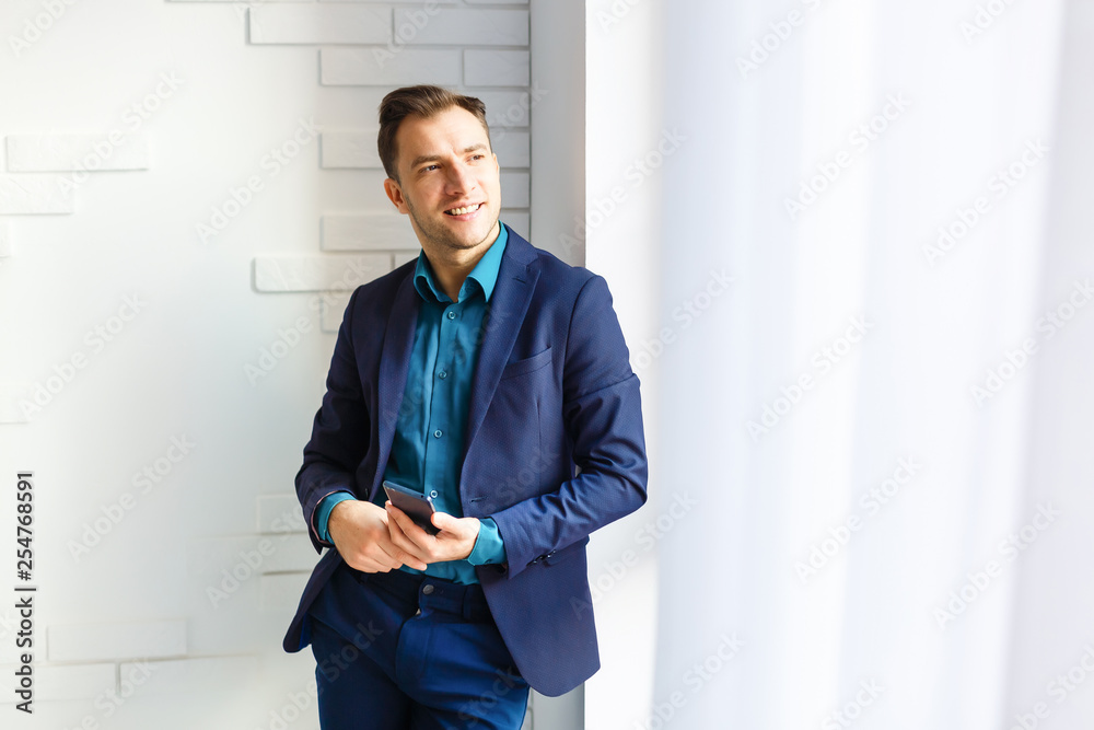 Handsome businessman in suit and eyeglasses speaking on the phone in office Handsome businessman in suit and eyeglasses speaking on the phone in office