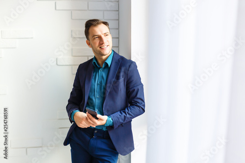 Handsome businessman in suit and eyeglasses speaking on the phone in office