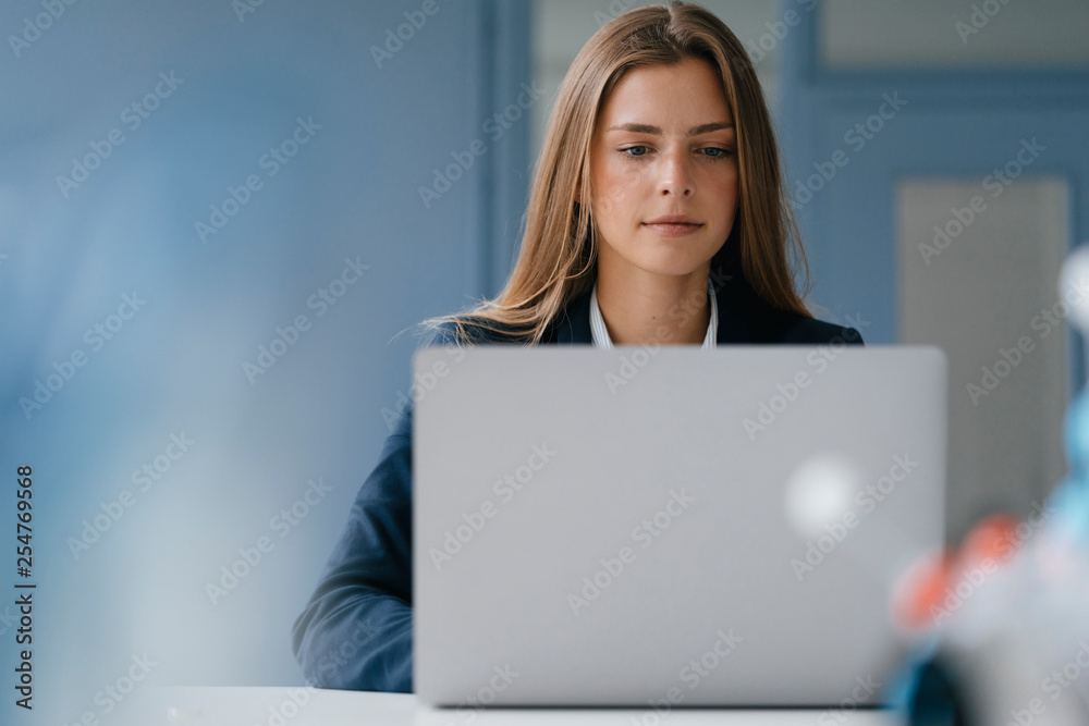 Portrait of a young businesswoman, working in office, using laptop Portrait of a young businesswoman, working in office, using laptop