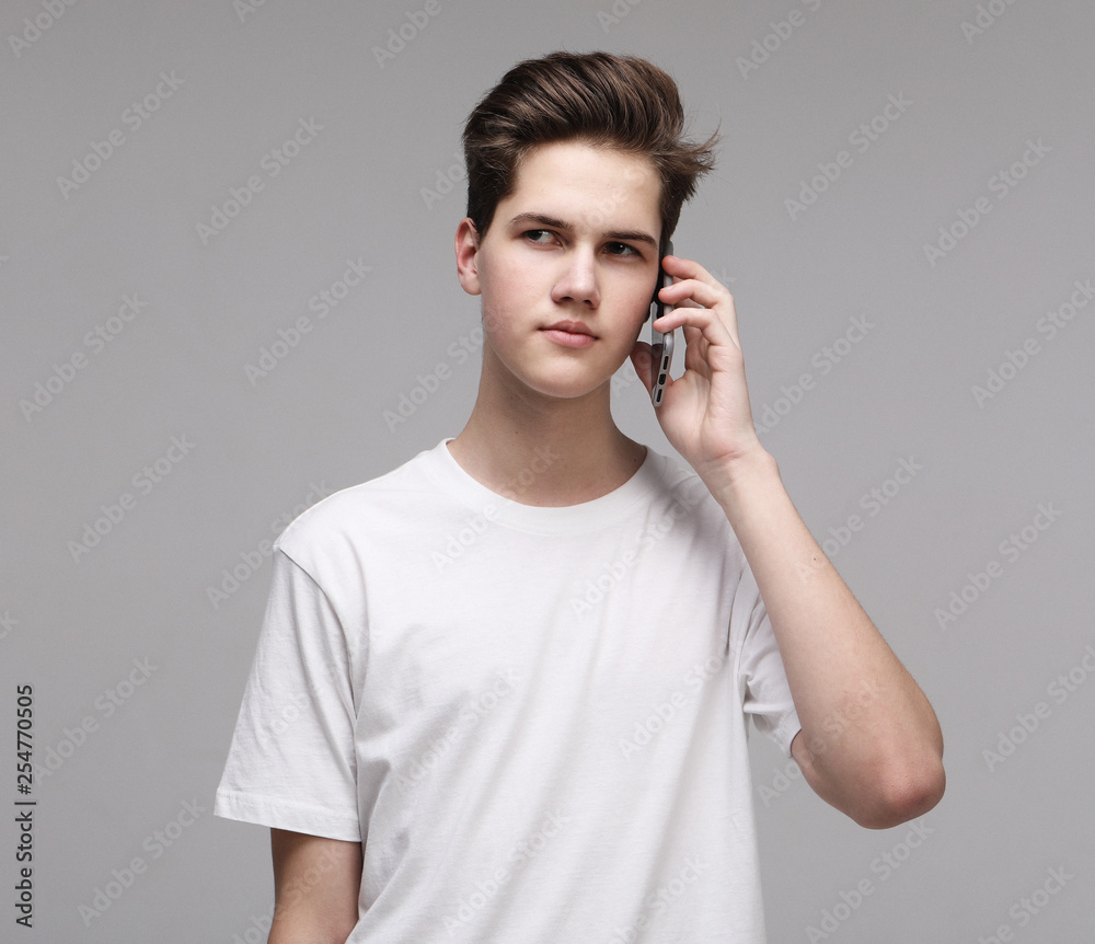 Smiling man in t-shirt talking by smartphone over grey background Smiling man in t-shirt talking by smartphone over grey background