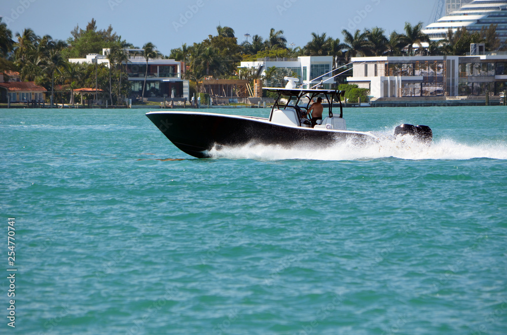 Fototapeta premium Black sports fishing boat with white trim powered by three outboard engines speeding on the Florida Intra-Coastal Waterway