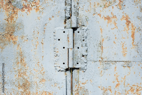 Old iron wall with door hinge covered by white paint. Abstract background.