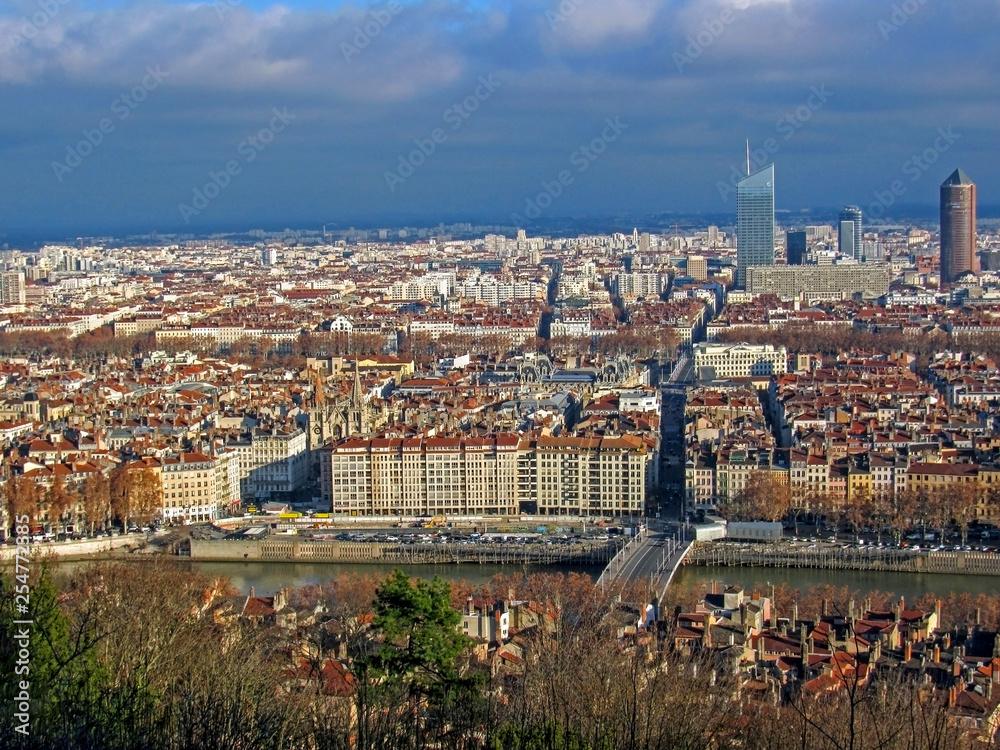 Aerial view of the city wide panorama with landmarks surrounded by red rooftops and chimneys, Lyon, France