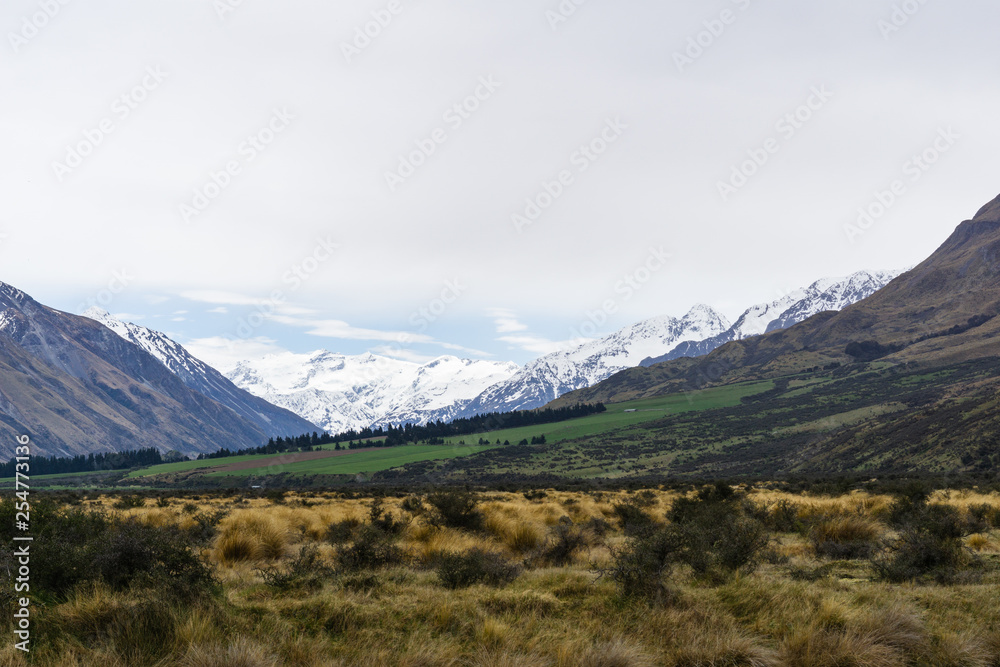 mountain landscape in the mountains, beautiful vast valley with mountains on the horizon, mountain peak covered by snow, during hazy day