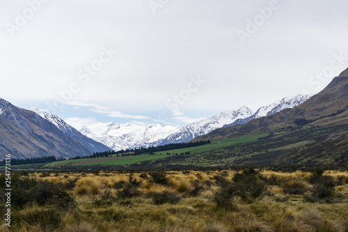 mountain landscape in the mountains, beautiful vast valley with mountains on the horizon, mountain peak covered by snow, during hazy day