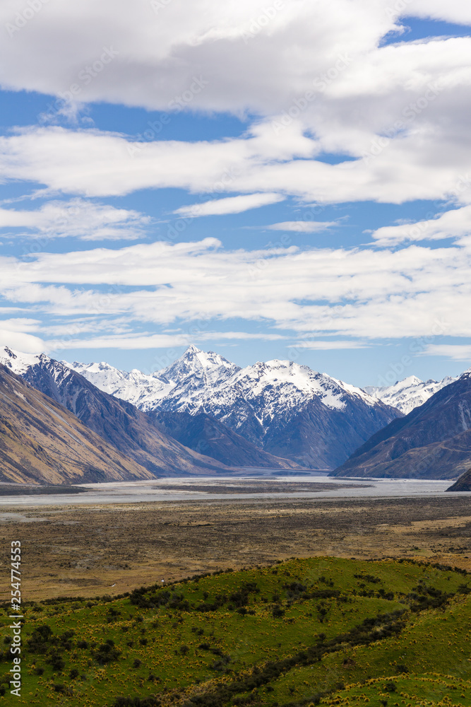 Beautiful vast valley with mountains on the horizon, mountain peak covered by snow, during sunny with dramatic sky, mountain landscape