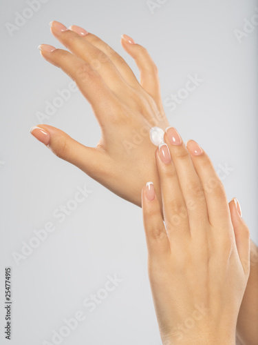 Woman applies a cosmetic moisturizer on her hands.