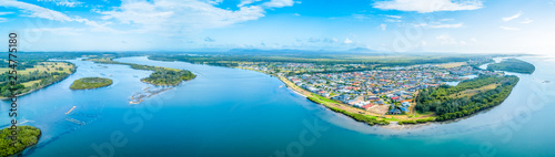 Aerial panorama of picturesque small coastal village and river at sunset in New South Wales, Australia