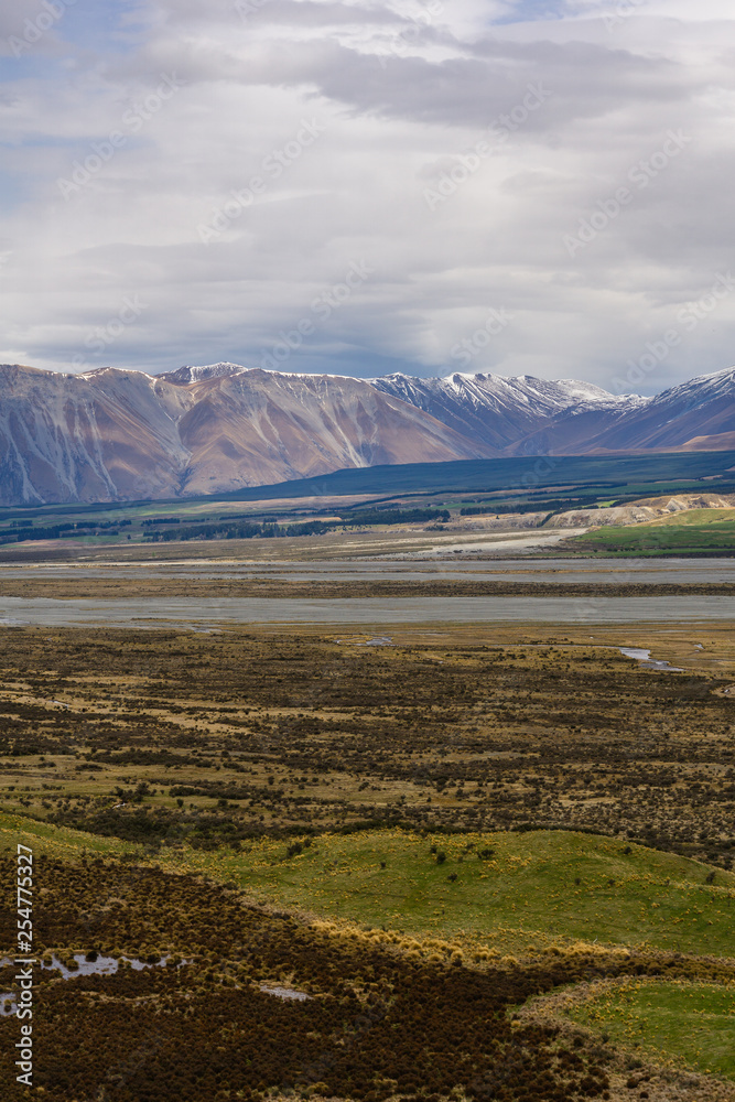 Beautiful vast valley with mountains on the horizon, snowy mountain peaks, during sunny with dramatic sky