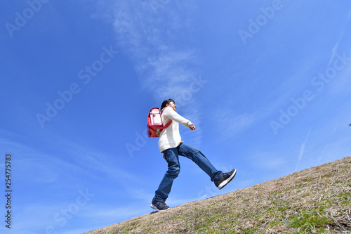青空で走る小学生の女の子（ランドセル） © hanapon1002