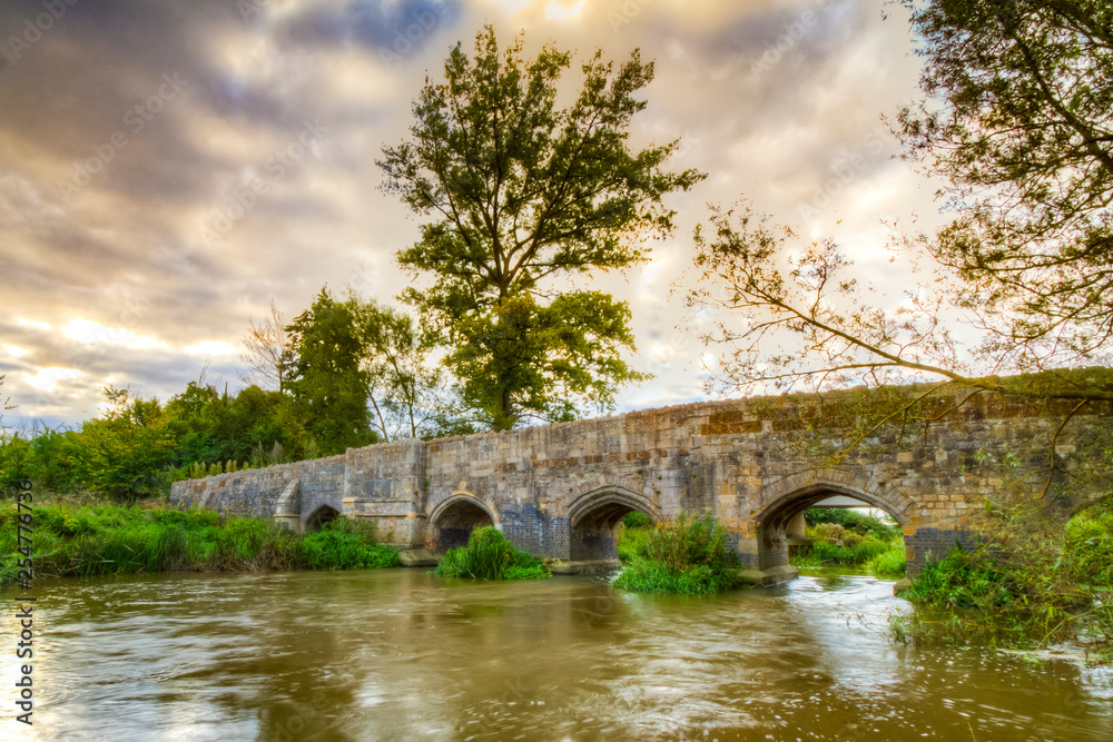 Old stone medival bridge over a streaming river