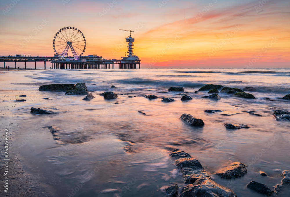 Colorful sunset on coastline, beach, pier and ferries wheel, Scheveningen, the  Hague. Stock Photo