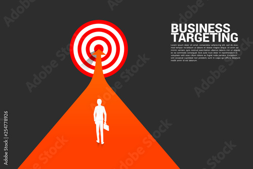 silhouette of businessman walking on arrow to center of dartboard. Business Concept of targeting and customer.Company vision mission.