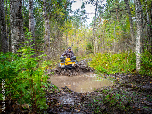 A man rides on ATV through the mud. Riding a quad bike. A man rides an all-terrain vehicle. Riding off-road on an ATV. Outdoor activity. Extreme. Rent a quad bike.