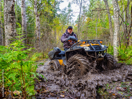 A man rides on ATV through the mud. Riding a quad bike. A man rides an all-terrain vehicle. Riding off-road on an ATV. Outdoor activity. Extreme. Rent a quad bike.