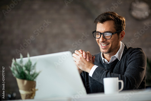 Happy male entrepreneur using laptop while working in the office.