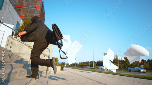 CLOSE UP: Businessman running late to work and losing important paperwork.