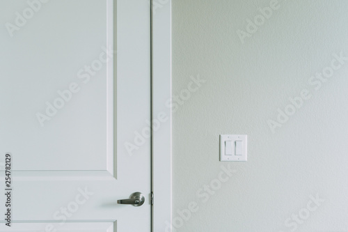 White door with visible handle. Olive drywallwith light switch on it.