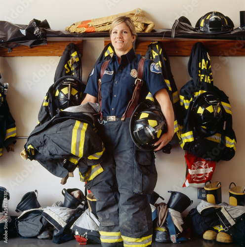 Portrait of female firefighter with helmet standing in fire station