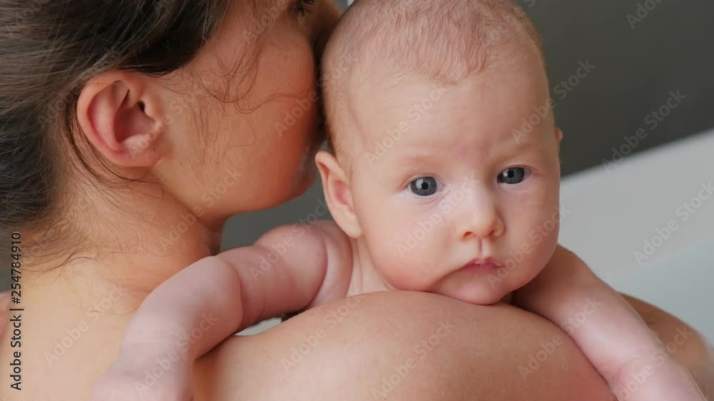 Portrait of a three months old baby girl, resting firmly on her mothers arms making a gentle smile, closeup Portrait of a three months old baby girl, resting firmly on her mothers arms making a gentle smile, closeup
