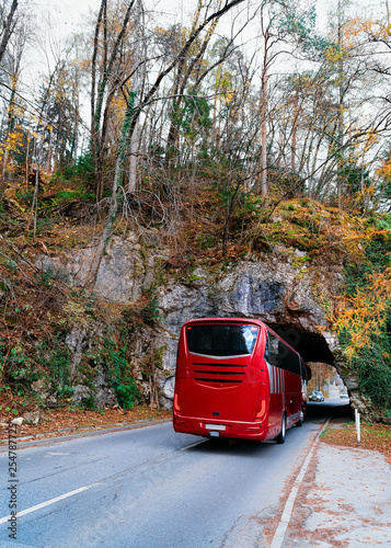 Red bus on road at tunnel in mountains in Bled