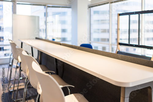 Modern empty office room lunch kitchen bar in building with wooden corporate business table closeup by glass window and many row chairs nobody