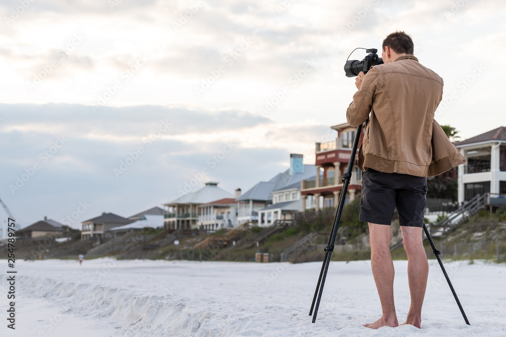 Santa Rosa Beach, Florida with back of young man photographer standing taking picture looking at coastline buildings