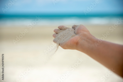 Fototapeta Naklejka Na Ścianę i Meble -  Freedom, Let it go and Release concept. Freedom Hand of woman release sand on beautiful seabeach and blue water background.