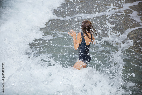 Young girl jumping in big waves with water splashing around