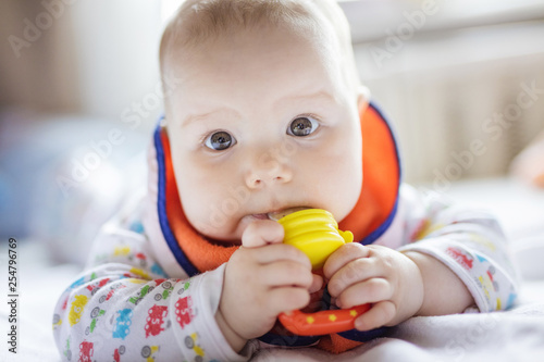 Cute baby eating fruit in nibbler on bed at home photo