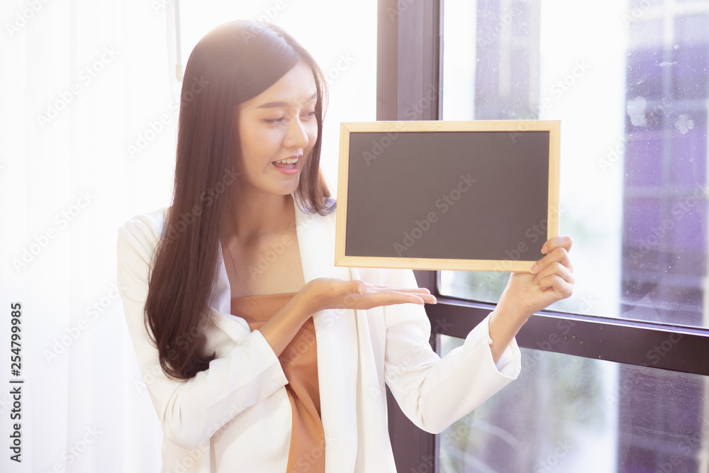 young Asian business woman holding a chalkboard.Successful business woman happy and smile.Idea note on blank blackboard. young Asian business woman holding a chalkboard.Successful business woman happy and smile.Idea note on blank blackboard.