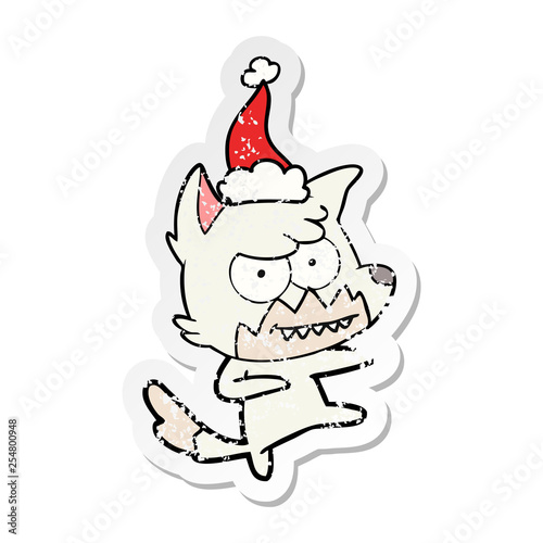 distressed sticker cartoon of a grinning fox wearing santa hat