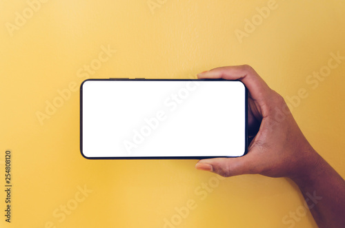 Human hand holding smartphone with white screen background.