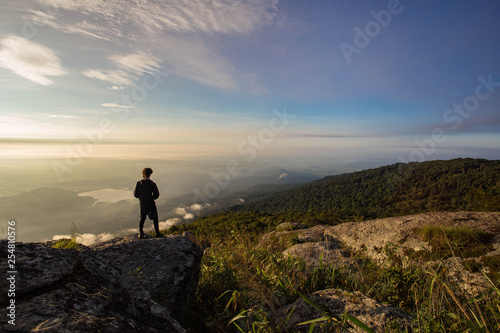Silhouettes of man standing on top mountain and looking sunset. © nidsornkul1989