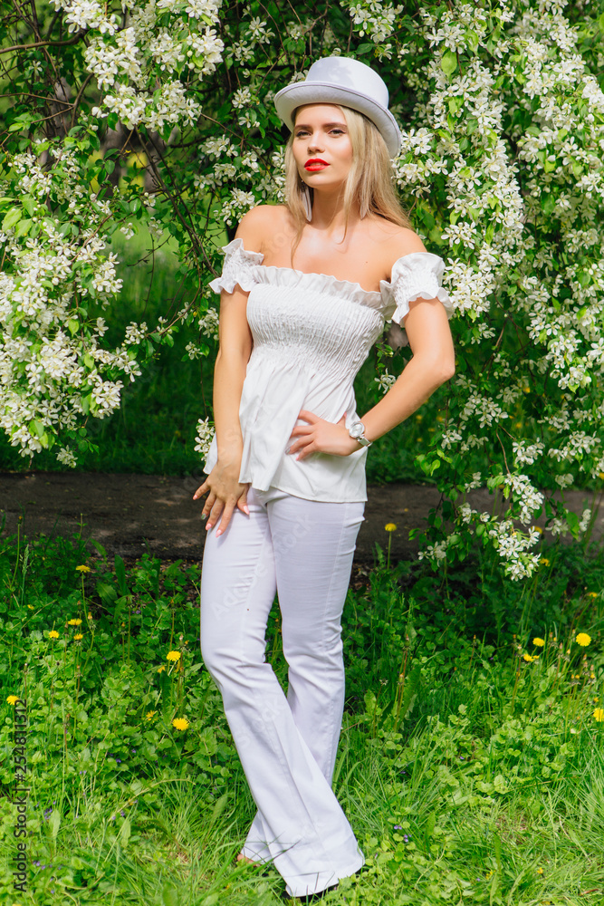 Sexy modern bride in white cylinder hat enjoing bloomin apple tree flowers. Sexy modern bride in white cylinder hat enjoing bloomin apple tree flowers.