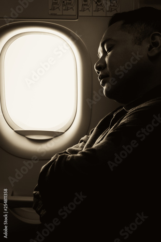 young man sleeping in an airplane window seat