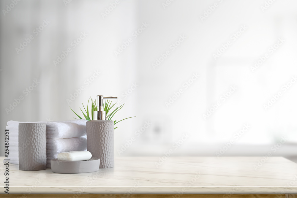 Towels and ceramics shampoo or soap on top marble table with copy space on blurred bathroom background.