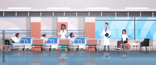 doctors team visiting disabled mix race patients sitting wheelchair lying bed intensive therapy ward healthcare concept hospital clinic room interior horizontal