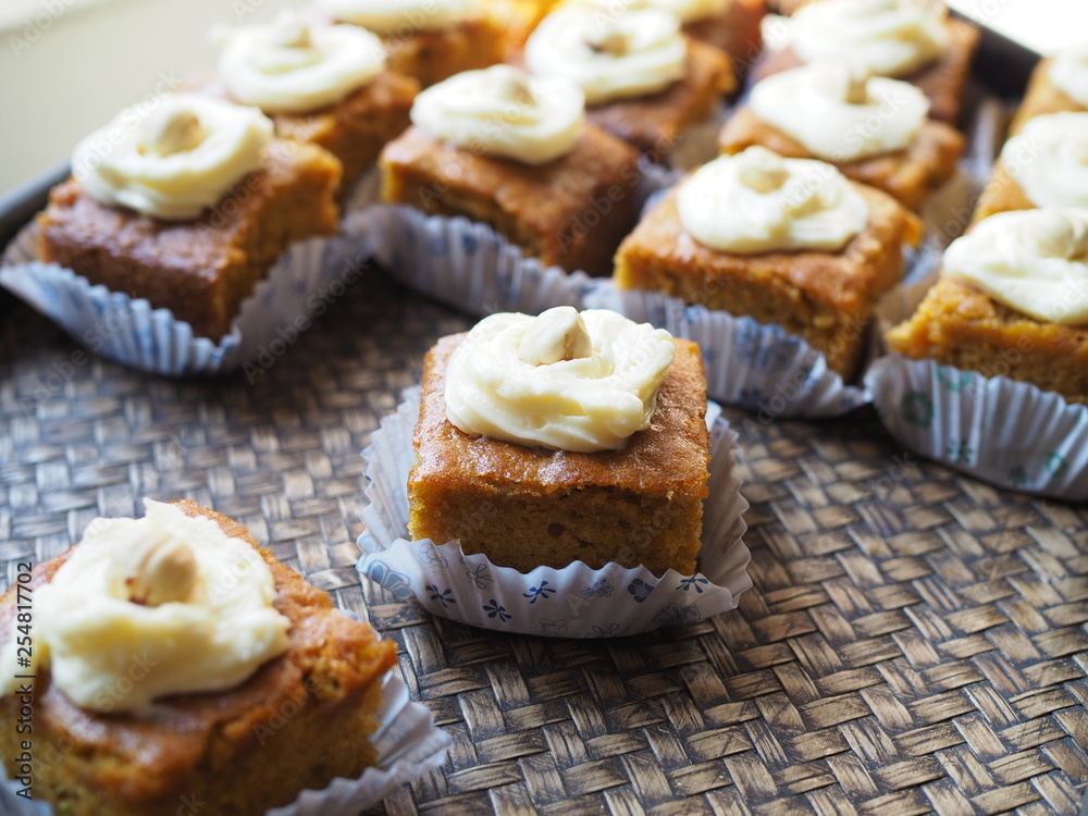 Slice of carrot cake with cream cheese frosting on wooden tray Slice of carrot cake with cream cheese frosting on wooden tray