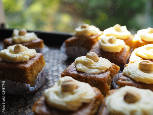 Slice of carrot cake with cream cheese frosting on wooden tray