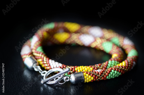 Beaded necklace with geometry print on a dark background close up