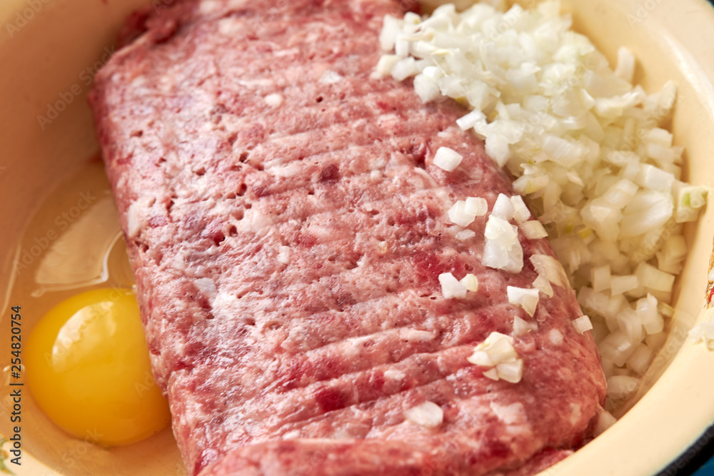 fresh beef and pork minced meat sprinkled with white onions and chicken egg for making cutlets and schnitzel in a yellow iron plate fresh beef and pork minced meat sprinkled with white onions and chicken egg for making cutlets and schnitzel in a yellow iron plate