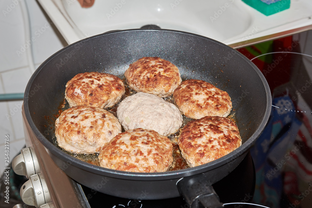 Beef and pork meat patties are roasted in a pan on a gray-colored electric stove in the kitchen at home. homemade delicious food. cooking at home. Beef and pork meat patties are roasted in a pan on a gray-colored electric stove in the kitchen at home. homemade delicious food. cooking at home.