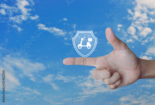 Motorcycle with shield flat icon on finger over blue sky with white clouds, Business motorbike insurance concept