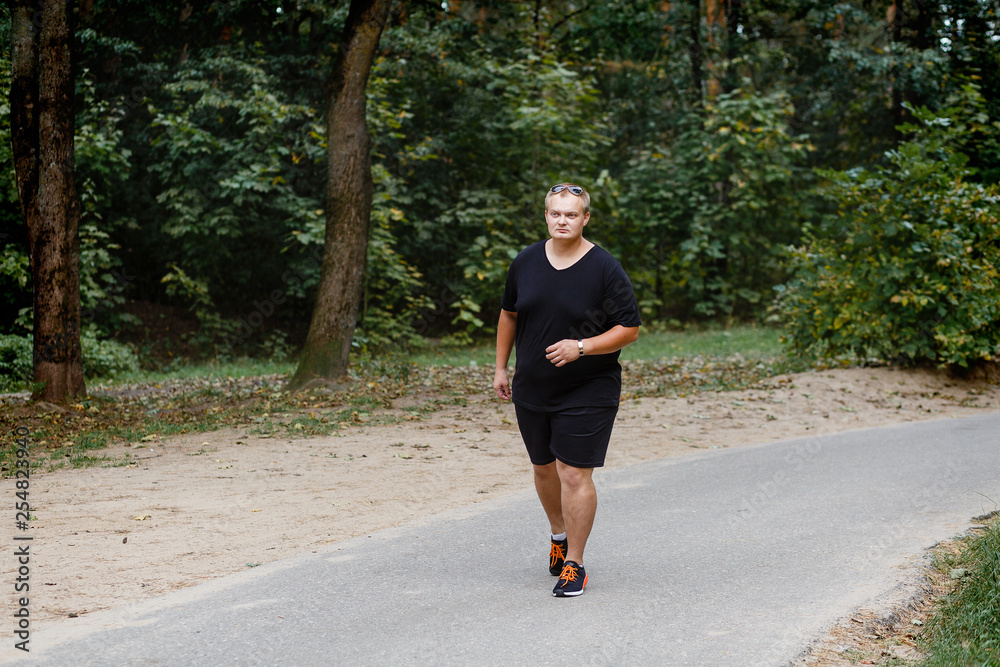 Fototapeta premium very fat guy runs in the park in summer