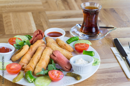 Appetiser plate with Turkish pastry (borek), onion rings, sausages and sauces 