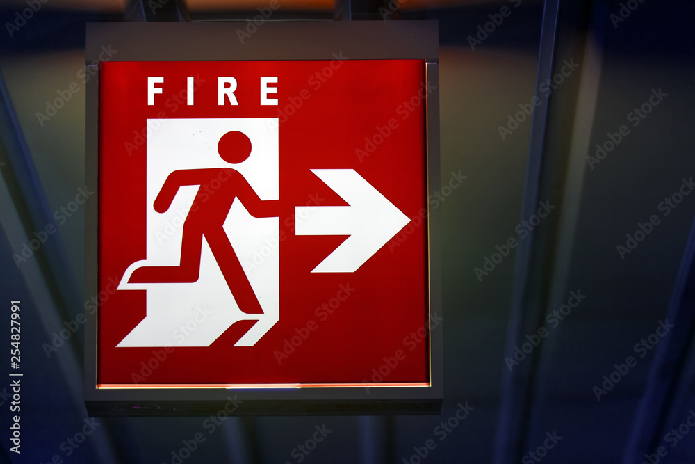 The emergency sign for fire shows the direction of flame. The riskly exit for fire board hangs on the ceiling of the building. The emergency sign for fire shows the direction of flame. The riskly exit for fire board hangs on the ceiling of the building.